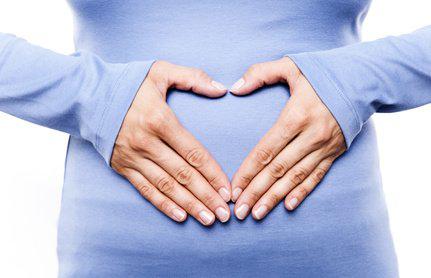 Heilpraktiker Colitis Ulcerosa und Morbus Crohn Frau formt ein Herz auf Höhe des Darms, der von Heilpraktikern bei Colitis Ulcerosa und Morbus Crohn behandelt wird