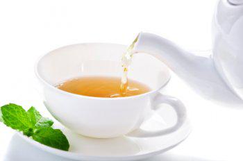 Tee hat bestimmte Wirkungen in der 5 Elemente Ernährung Eingießen einer Tasse Kräutertee, der in der TCM gesundheitsfördernd ist